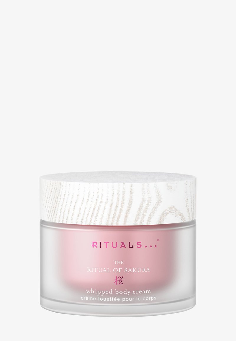 Vispad kroppskrämsburk med frostat glasunderlag, rosa insida och ett texturerat vitt trälock. Har rosa varumärkestext.