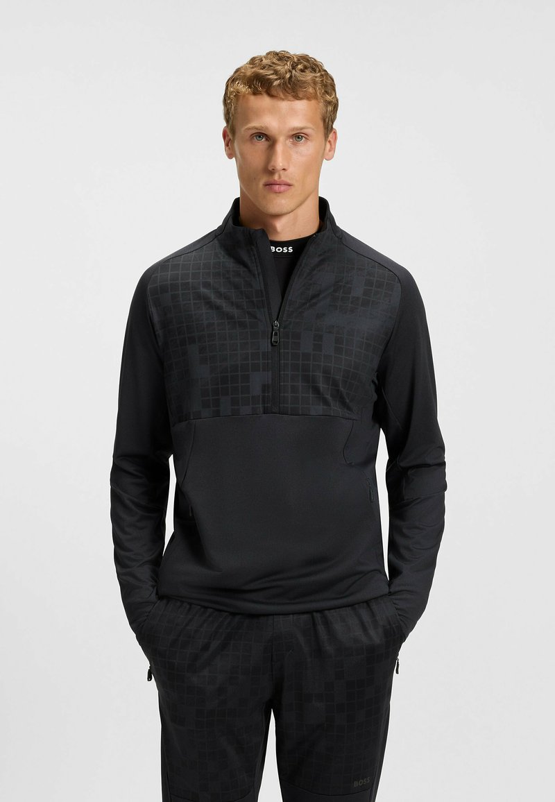 Pullover sportivo nero con zip a un quarto, caratterizzato da una parte superiore testurizzata con sottili motivi geometrici e maniche e corpo lisci.