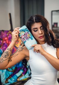 Modrá peněženka s grafikou zobrazující karikaturu, obklopená tropickým listím. Materiál vypadá synteticky s lesklým povrchem.