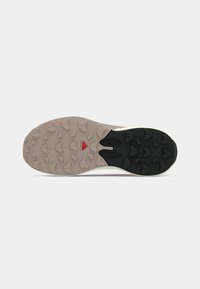 Semelle de basket avec un schéma de couleurs noir et beige, présentant une texture en caoutchouc antidérapante avec des crampons angulaires pour l'adhérence et la durabilité.