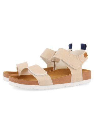 Beige sandalen met open neus en verstelbare stoffen bandjes, een bruin voetbed, een witte zool en donkerblauwe trekbandjes op de hiel.