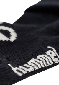 Schwarze Strümpfe aus Wolle mit weißem Text, die eine weiche Textur und eine enge Passform bieten. Das Design umfasst ausgeprägte Musterakzente.