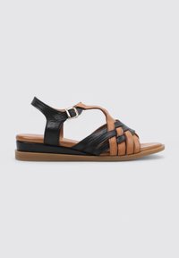 Sandalias de cuero negras y marrones con diseño trenzado, correa ajustable con hebilla, suela plana y plantilla marrón lisa.