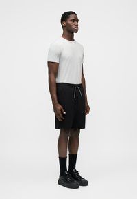 Γκρι κοντομάνικη μπλούζα συνδυασμένη με μαύρα σορτς φόρμας. Το μοντέλο φοράει μαύρα αθλητικά παπούτσια και κάλτσες. Απλός σχεδιασμός, άνετη εφαρμογή και ουδέτερα χρώματα.