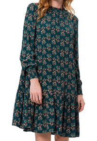Vestido floral de manga larga en verde oscuro, con escote fruncido, puños elásticos y un dobladillo acampanado con volantes en capas.