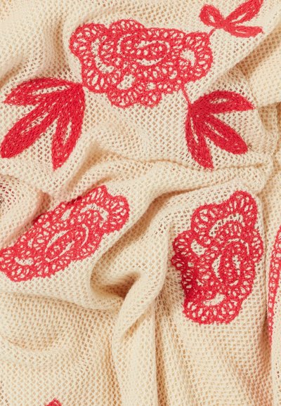 Tessuto beige lavorato a maglia con ricamo floreale rosso con rose e foglie in un motivo strutturato leggermente stropicciato.