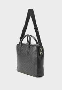 Bolso de viaje negro con patrón de diamante, lados de cuero, doble asa superior y correa ajustable y desmontable; diseño elegante con herrajes plateados.