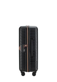 Black hard-shell suitcase with ridged texture, four spinner wheels, side handle, rose gold zipper, and built-in combination lock.