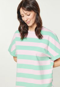 Stribede oversized T-shirt i vekslende mintgrøn og lyserød. Blødt stof med rund halsudskæring og opholdte korte ærmer.