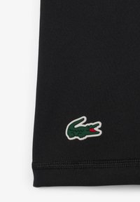 Tessuto nero con una superficie liscia, caratterizzato da un logo di coccodrillo verde e rosso su un contorno bianco nell'angolo in basso.