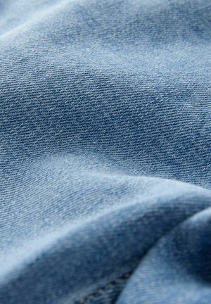Lysblåt denimstof med en synlig twill-vævstruktur. Glat og let krøllet udseende med subtil syning.