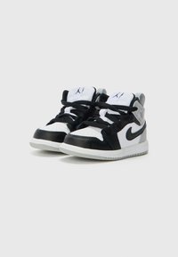 Baskets athlétiques noires et blanches avec une tige en cuir, un col rembourré et une semelle en caoutchouc texturé. Dotées de lacets noirs et d'un logo Jordan.
