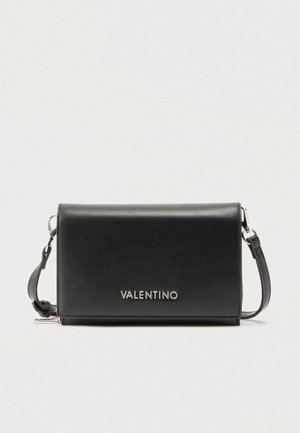 Schwarze Valentino Crossbody-Tasche aus Leder mit silbernem Logobuchstaben und verstellbarem Riemen auf hellem einfarbigem Hintergrund.