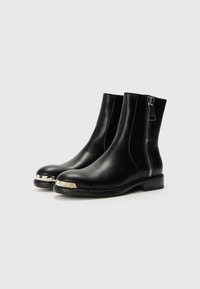 Botas de cuero negras hasta el tobillo con punta redondeada, punta metálica y cremallera lateral. Suela resistente con detalles de costura visibles.