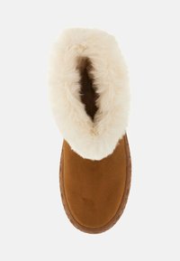 Bruine suède enkellaars met een fluffige crèmekleurige nepbont bovenkant. Rond de tenen en met een gestructureerde rubberen zool voor grip en comfort.