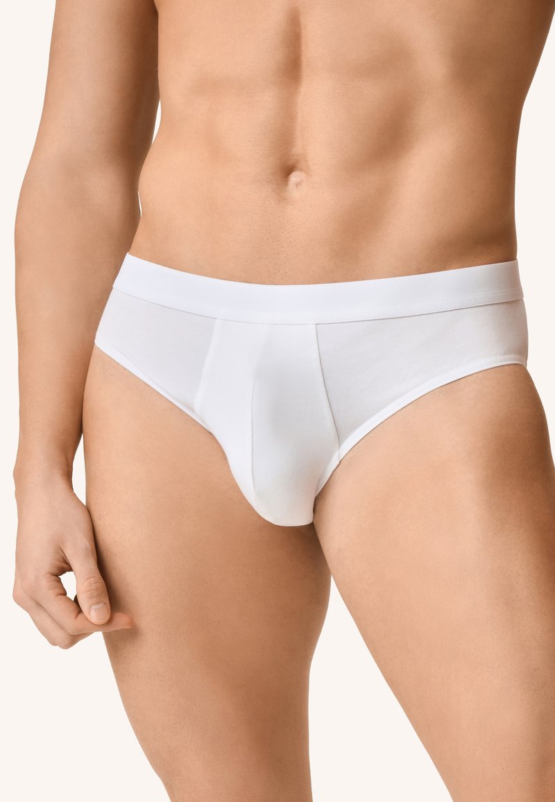 Slip di cotone bianco con una texture liscia, caratterizzati da un design aderente e una vita piatta, che enfatizza una silhouette affusolata.