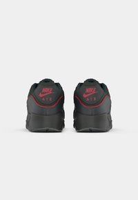 Par crnih i crvenih Nike Air tenisica prikazanih s leđa, s logotipom Nike i Air oznakom na petnom dijelu.