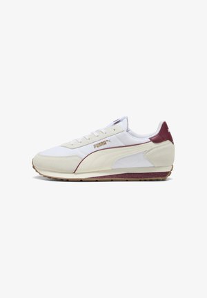 Zapatilla blanca con acentos de ante en burdeos y beige. Presenta una suela texturizada y un diseño con cordones. Nombre de la marca en dorado.