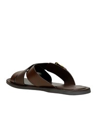 Brown leather slide sandal featuring crossed straps, a textured panel, and a flat rubber sole. Notable gold hardware accent present.