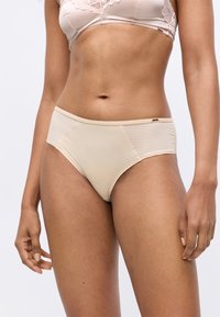 Beige, hochtaillierte Unterwäsche aus glattem Stoff mit gerippten Seitenbesätzen. Elastischer Bund, minimale Details und klassischer Schnitt.