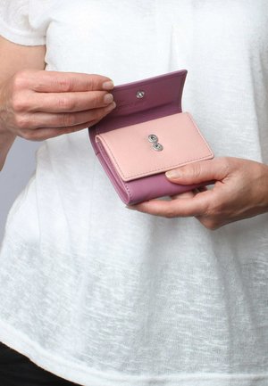 Rosa und lila Leder Geldbörse mit Druckknopfverschluss, ausgestattet mit zwei runden metallischen Akzenten auf der Vorderseite. Kompakt, mit sanfter Textur.