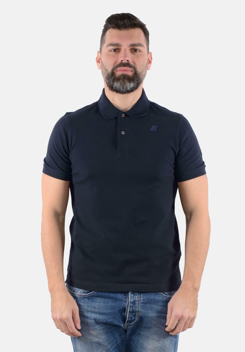 Polo shirt blu navy con maniche corte, colletto e chiusura a bottoni. Presenta un piccolo logo sul lato sinistro del petto e una texture simile al cotone.