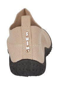 Helle beige Wasserschuhe mit einem strukturierten, dehnbaren Oberschuh und einer schwarzen Gummisohle, ausgestattet mit einem Zugband und der Aufschrift "SWIM" auf der Rückseite.