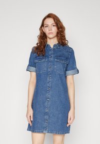 Jeansskjortklänning i blått, med korta uppvikta ärmar, två bröstfickor, knäppning fram och böjd fåll. Tillverkad av ett lätt denimmaterial.