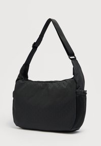 Μαύρη τσάντα ώμου από νάιλον με υφασμένο γεωμετρικό σχέδιο, ρυθμιζόμενο λουράκι και δίχτυ πλαϊνή τσέπη. Απλός, λειτουργικός σχεδιασμός.