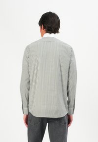 Stripet langermet skjorte i grønn og hvit, laget av lett stoff, med klassisk krage og knappeermer, som viser en tettsittende bakdesign.