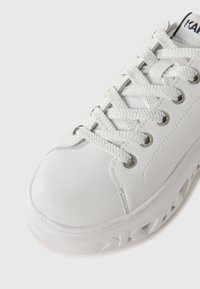 Sneaker sintetico bianco con punta tonda, superficie testurizzata, occhielli metallici e lacci piatti. Presenta una suola spessa, stratificata e a motivo.