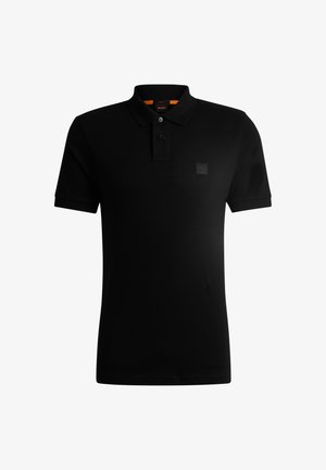 Polo negro hecho de algodón, con cuello, tapeta de dos botones y un parche de logo en goma en el pecho. Manga corta.