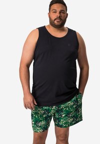 Canotta nera con scollatura rotonda abbinata a pantaloni da bagno verdi a fiori, caratterizzati da una varietà di motivi a foglia in tonalità scure e chiare.