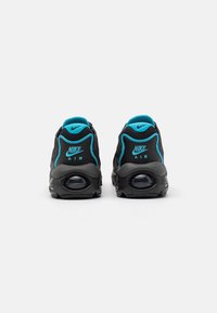 Svarta Nike Air-sneakers med en texturerad yta, med turkosa accenter och en synlig luftkudde i sulan.