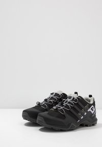 Zapatos de senderismo negros con un upper texturizado, que presentan acentos grises, un sistema de cordones asegurado y una suela robusta para tracción.