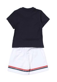 T-shirt in cotone navy a maniche corte con colletto rotondo, abbinato a pantaloni cut-off bianchi con strisce rosse e navy all'orlo.
