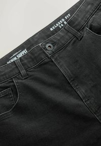 Fekete, laza szabású farmernadrág gombos zárással és öt zsebes kialakítással. Kiemelkedő derékszallagos címkével rendelkezik, amelyen a "Denim Supply" felirat szerepel.