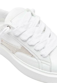 Białe sneakersy z skórzaną cholewką z teksturowanymi akcentami, puszystymi sznurówkami i kontrastującą beżową wstawką po boku. Gumowa podeszwa.