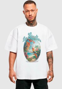 Balta per didelį T-shirt su spalvingu tropiniu papūga grafika, apsupta gėlių ir palmės lapų, viršuje esantis tekstas "2y Studio".