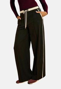 Zwarte wide-leg broeken met een beige trekkoord taille, met zijzakken en contrasterende witte zijstrepen. Gestructureerde stof.