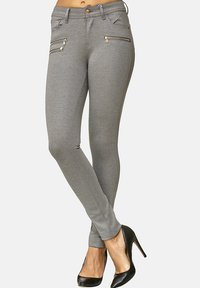 Pantaloni grigi alla caviglia con taglio aderente, dotati di due tasche frontali con zip e realizzati in un tessuto liscio e testurizzato.