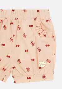 Peachfarvede shorts med kirsebærmønster, elastisk talje, flæse lommer og et hjerteformet guldlogo som accent. Fremstillet af blødt stof.