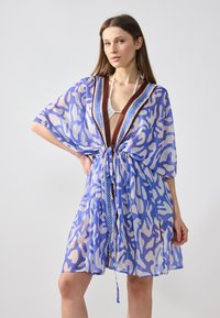 Cubierta transparente en tonos azules con patrones abstractos, presenta mangas anchas, un escote en V profundo y un cinturón ajustado en la cintura.