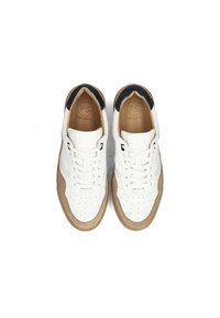 Zapatillas de cuero blanco con detalles perforados en la punta, acentos de ante marrón en los laterales y forro interior negro. Logotipo de la marca visible en la lengüeta.