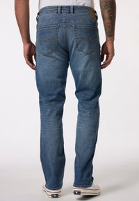 Vaqueros de denim azul desgastado con un diseño de pierna recta, bolsillos traseros con costuras decorativas y una etiqueta de cuero con la marca en la cinturilla.