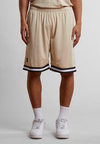 Shorts de sport beiges en tissu respirant, dotés d'un ourlet à rayures noir et blanc, d'une taille élastique et d'une coupe à longueur genoux.