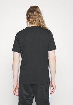 T-shirt en coton noir avec un col rond et des manches courtes, présenté de dos. Texture lisse, design simple et surface sans ornements.