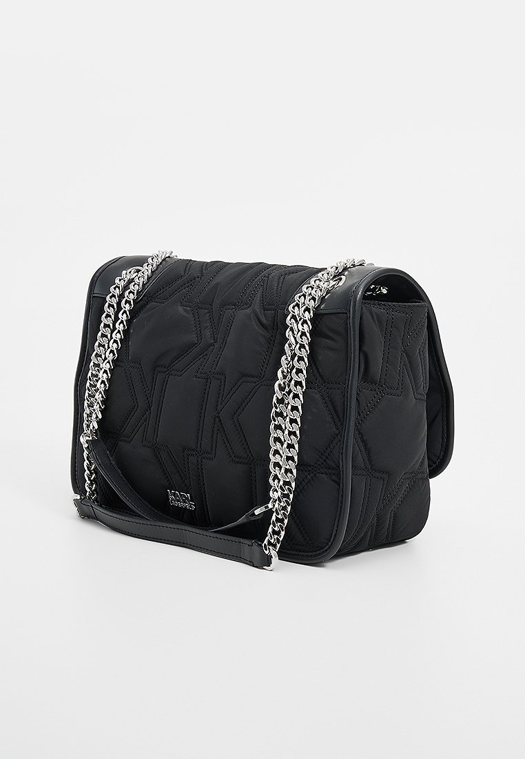 Sac à épaule noir matelassé avec un motif géométrique, une chaîne en bandoulière et des accents en cuir lisse. Présente un fermoir à rabat pour un accès facile.