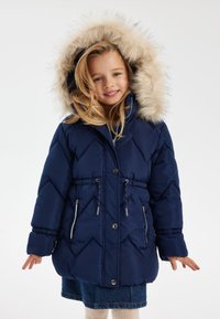 Blouson matelassé bleu marine avec capuche en fausse fourrure, design en losanges, taille à cordon de serrage et deux poches latérales zippées.