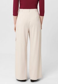 Beige wijde broek van een gladde stof, met een zijvak en een op maat gemaakte taille.
